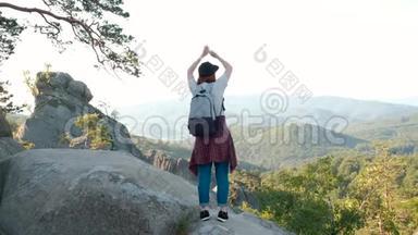 一位女士举着双臂<strong>站在山顶</strong>看着风景远足的女孩举起手臂庆祝风景